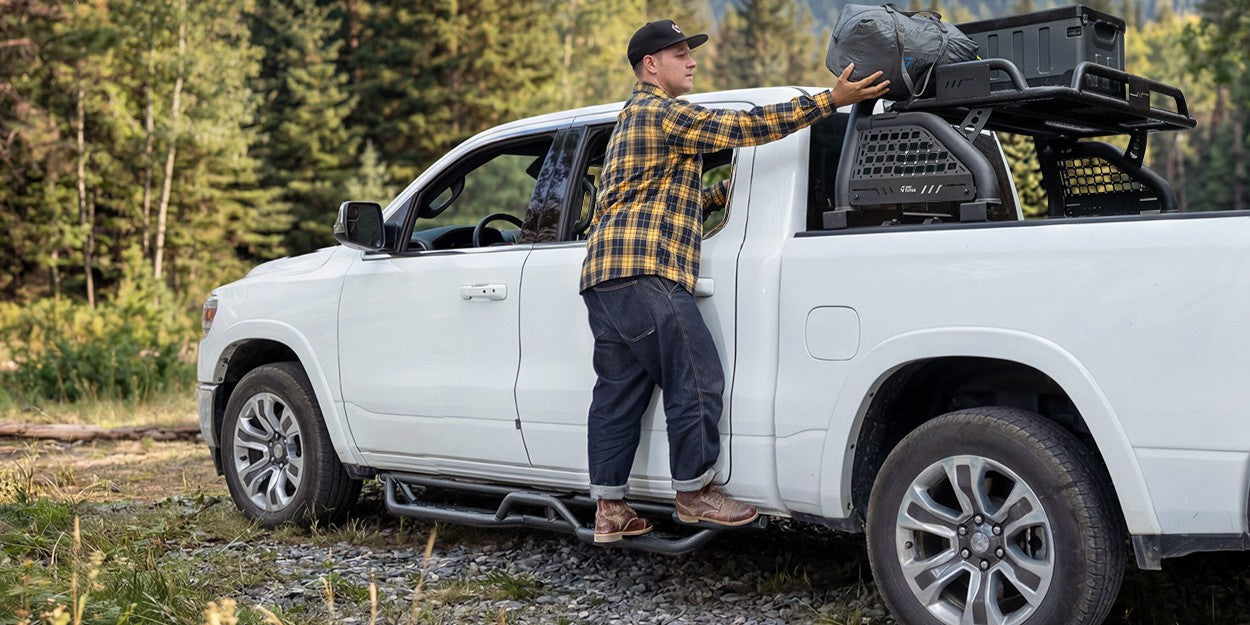 A man standing on pickup running boards is picking up items
